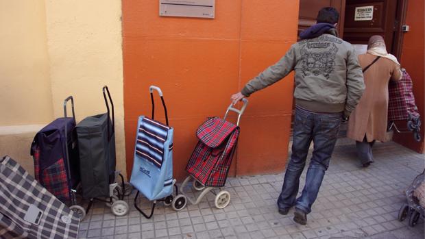 Personas necesitadas haciendo cola en un centro benéfico de reparto de alimentos, en Zaragoza