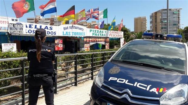 Una agente de la Policía Nacional junto a un coche patrulla