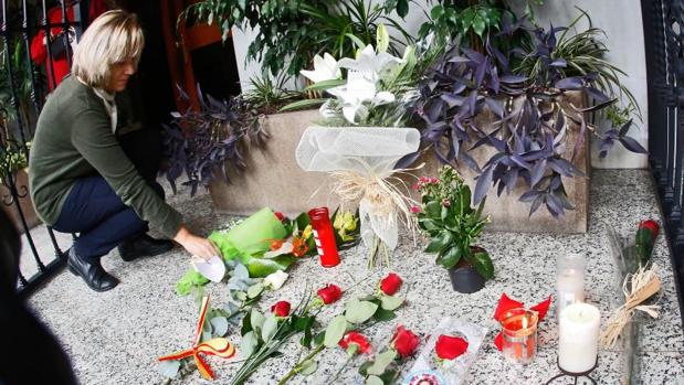 Una mujer deja un ramo de flores en el portal de Rita Barberá
