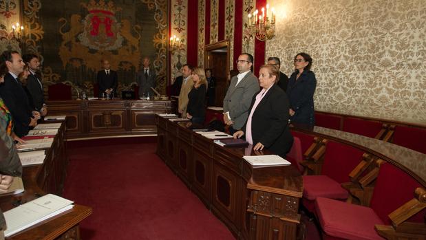 Los concejales en el minuto de silencio, con los asientos vacíos de Guanyar Alacant