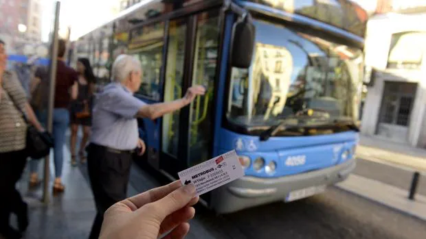 Un usuario muestra un billete de Metrobus, ante un autobús de la EMT
