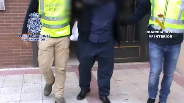Agentes de la Guardia Civil y la Policía Nacional llevan esposado a uno de los arrestados