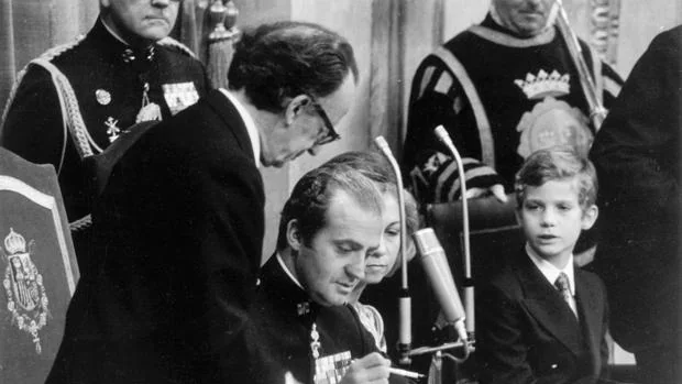 Don Juan Carlos rubricando la Constitución en presencia del entonces Príncipe de Asturias