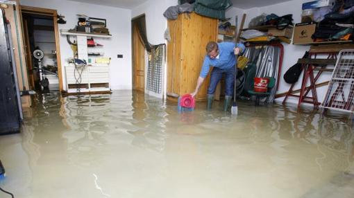 Un afectado por el temporal achica agua en su casa en Orihuela