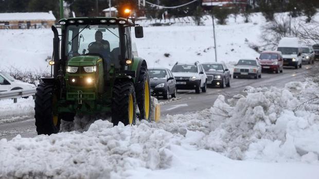 Un tractor limpia de nieve una carretera seguido por una cola de coches en Requena