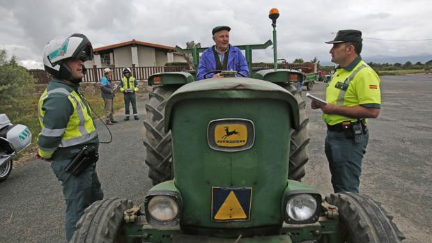 Dos agentes conversan con un anciano al volante de su tractor por una de las carreteras de la Comunidad