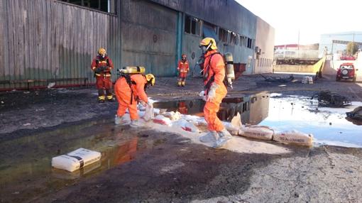 Los bomberos realizan una barrera de contención de un charco de agua ácida