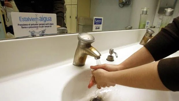 Una mujer se lava las manos bajo un grifo