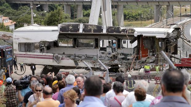 Un grupo de personas contempla la retira de los vagones del tren siniestrado en 2013