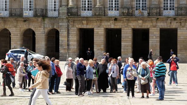 Un grupo de turistas atiende ayer las explicaciones de una guía en la plaza del Obradoiro de Santiago