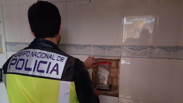 Un agente extrae cocaína escondida en una pared de la vivienda registrada