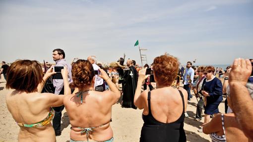 Unas bañistas toman fotos del Cristo del Salvador y del Amparo