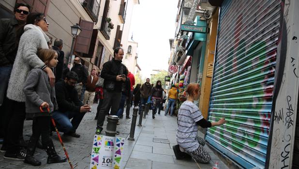 Una artista callejero pinta en el cierre de una tienda, durante la edición del año pasado