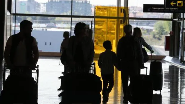 Varios pasajeros caminan con maletas por la terminal de un aeropuerto