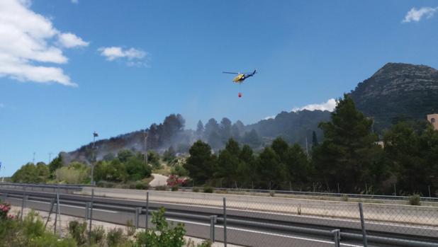 Un helicóptero lleva agua al incendio foestal en Terrateig