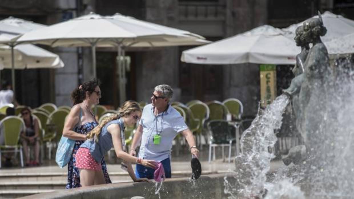 Unos turistas se refrescan en una fuente del centro de Valencia