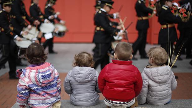 Varios niños contenplan una banda de Semana Santa