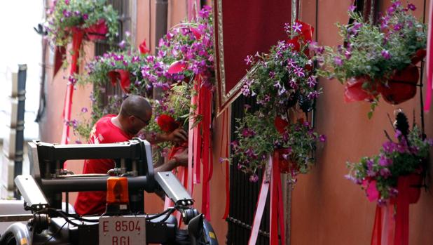 Un operario coloca las flores en las fachadas del recorrido procesional