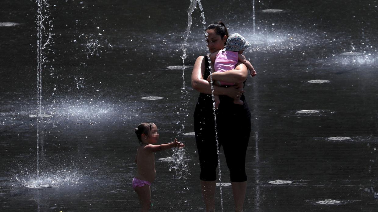 Una madre y sus dos hijos se refrescan bajo unas fuentes en Madrid