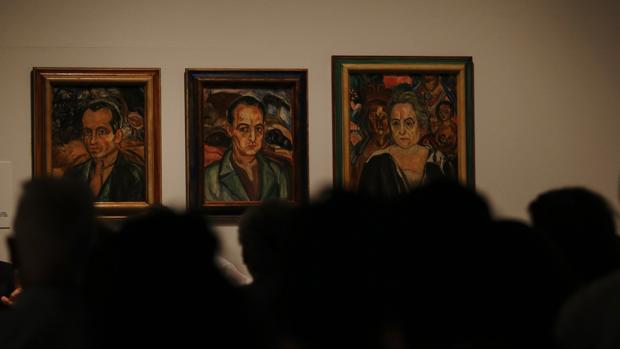 Unos visitantes observan unos retratos de Francesc Smith, Isaac Smith y Mónica Marí en el MNAC de Barcelona,