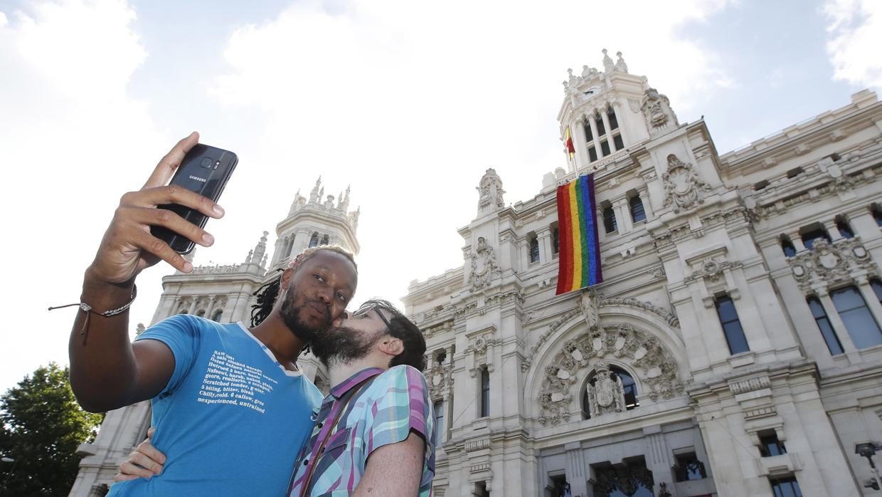 Una pareja se besa mientras se hace un «selfie» ante la fachada del Ayuntamiento de Madrid, donde luce la bandera arco iris