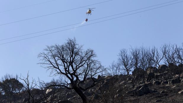 Un helicóptero trabaja en las labores de extinción del incendio producido ayer por la tarde en la sierra de Arroyo de Serván (Badajoz)