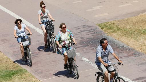 Unos turistas pasean en bicicleta por el cauce del río Turia de Valencia