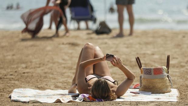Imagen del día de una chica con el móvil en la playa