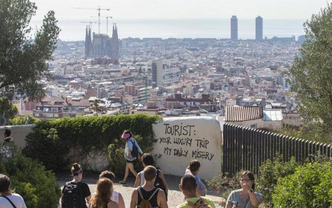 Turistas pasean por los alrededores del Parque Guell de Barcelona, donde han aparecido pintadas contra el turismo