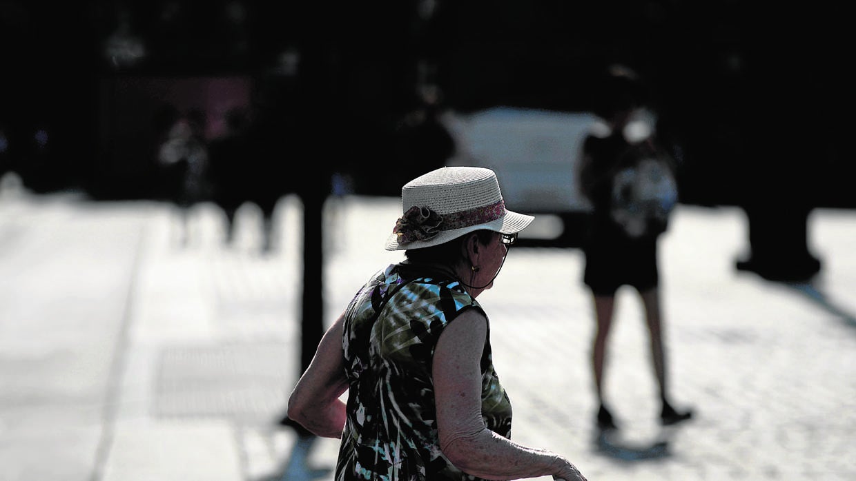 Una anciana paseando por una céntria plaza madrileña en plena canícula