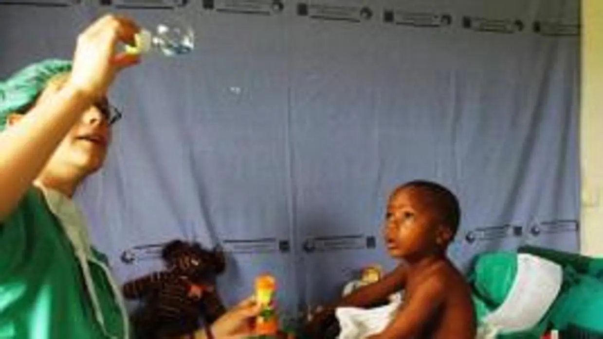 Una facultativa hace pompas de jabón para un pequeño paciente en Guinea