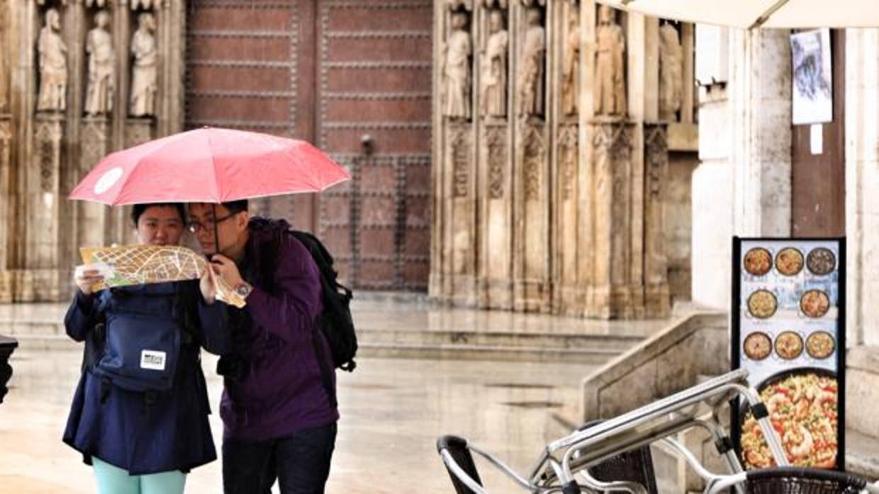 Unos turistas se protegen de la lluvia en una imagen de archivo captada en el centro de Valencia