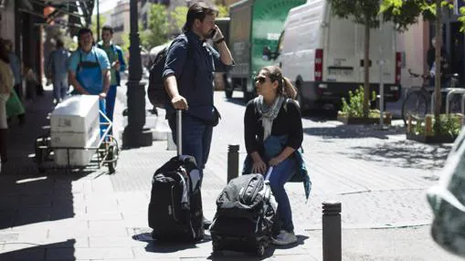 Dos turistas esperan con sus maletas, en el barrio de Lavapiés