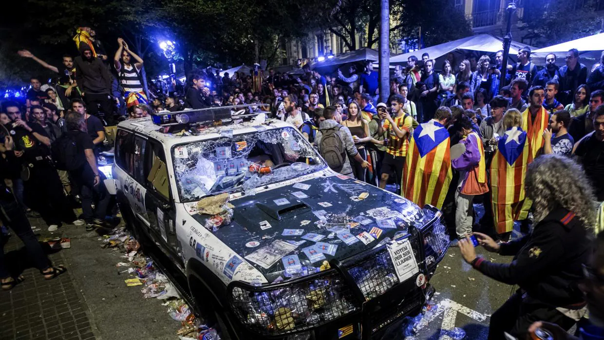 Un vehículo de la Guardia Civil, destrozado por los manifestantes, en Barcelona