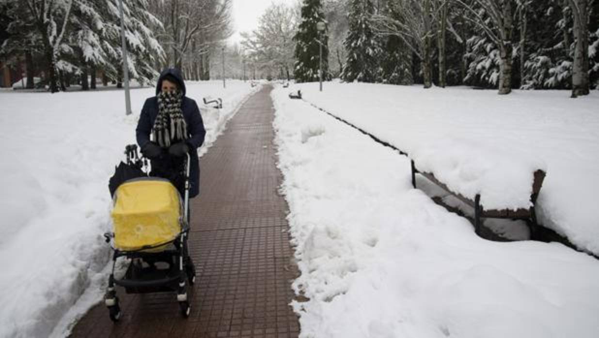 Un mujer pasea con un bebé por uno de los parques nevados de la ciudad de Vitoria