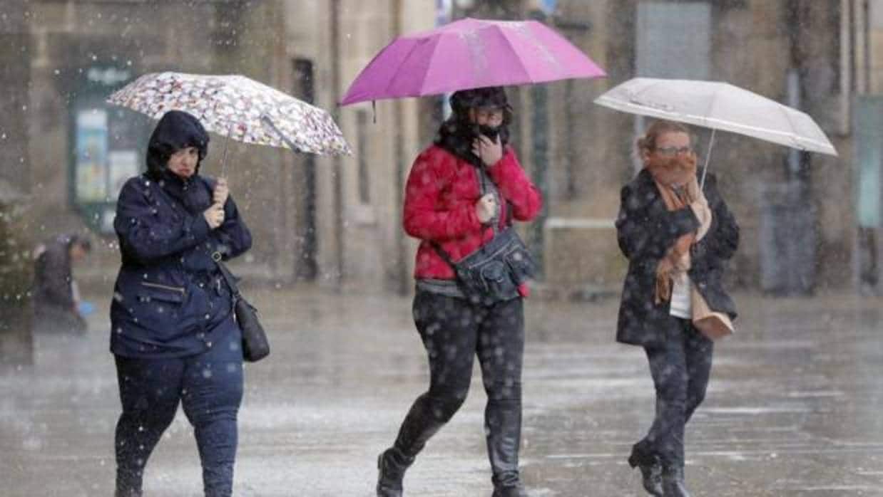 Tres mujeres se protegen de la lluvia durante la borrasca Ana