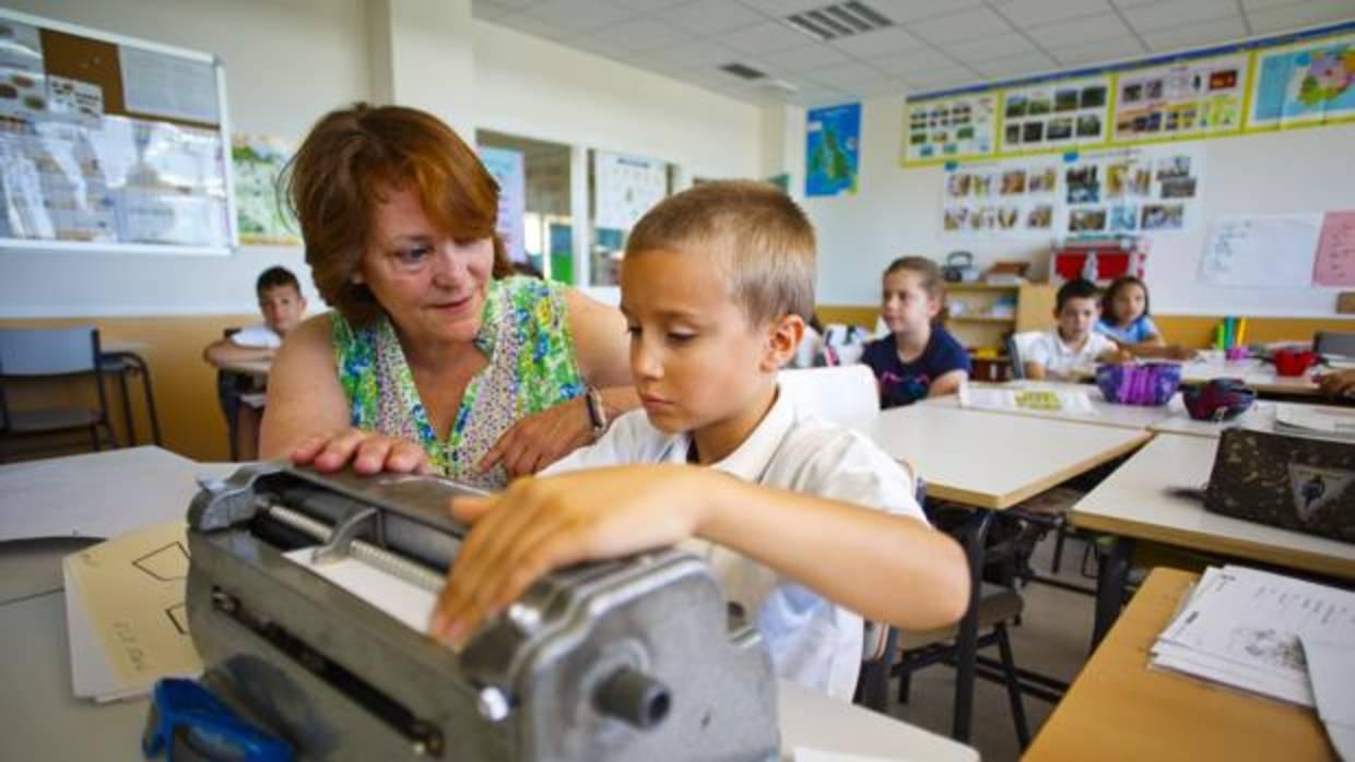 Un escolar con su profesora de apoyo de la ONCE