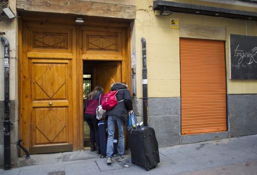 Dos turistas acceden al interior de un portal de la calle de Huertas