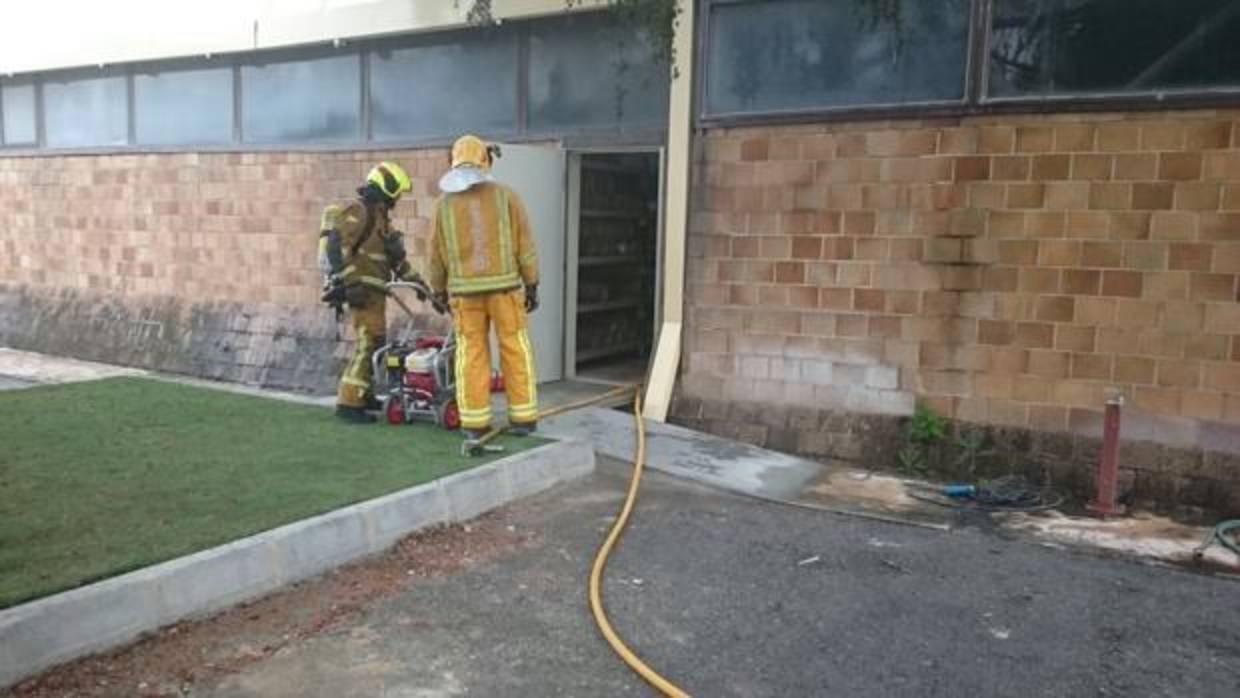 Dos Bomberos en una puerta de la fábrica donde se ha producido el incendio