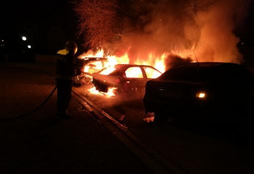 Un bombero trata de sofocar las llamadas en los coches incendiados en el barrio Santa María de Benquerencia,
