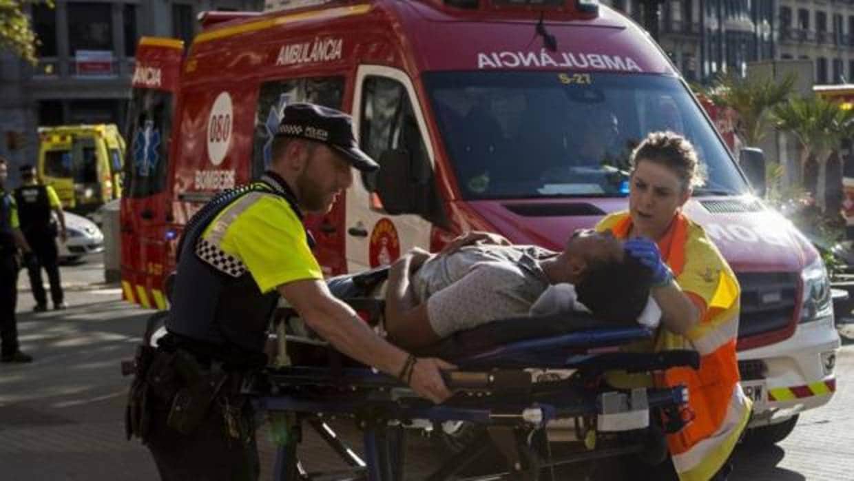 Un guardia urbano y una sanitaria atienden a un herido en el atentado de Las Ramblas de agosto