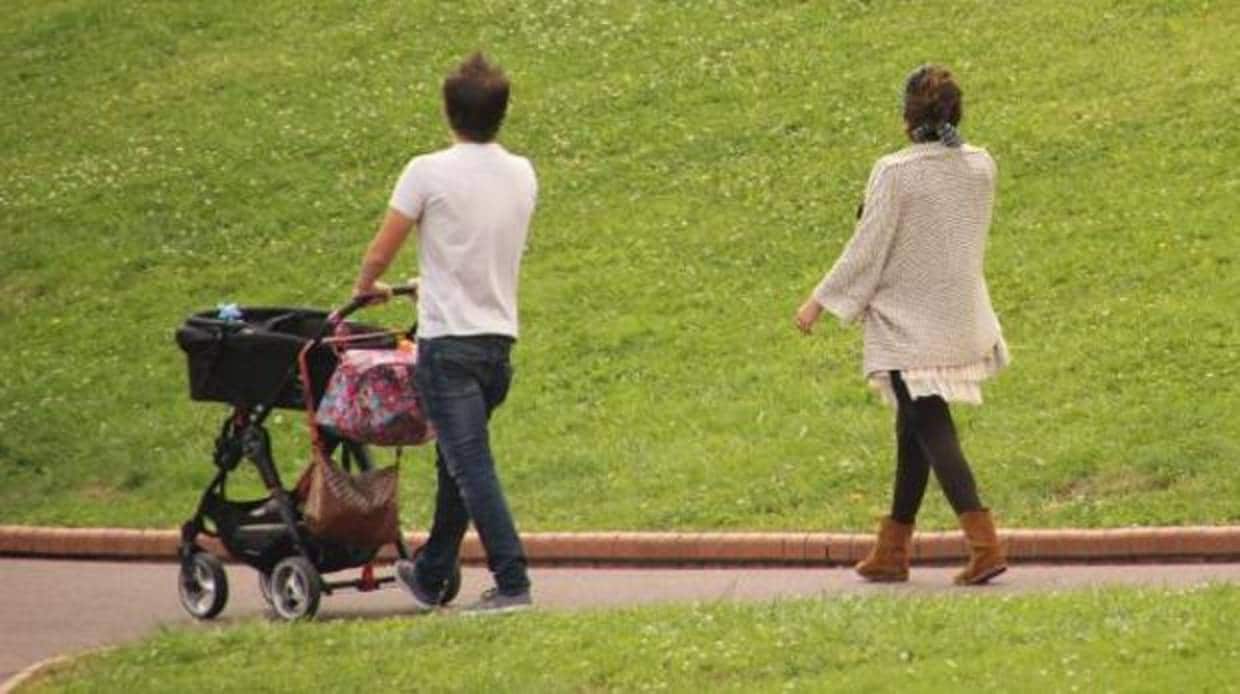 Una pareja pasea un bebé en el carrito