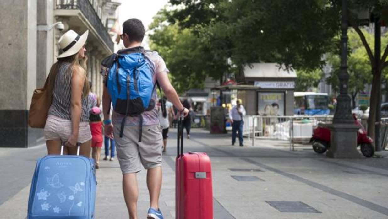 Dos turistas trasportan su equipaje por la calle de Alcalá, en Madrid