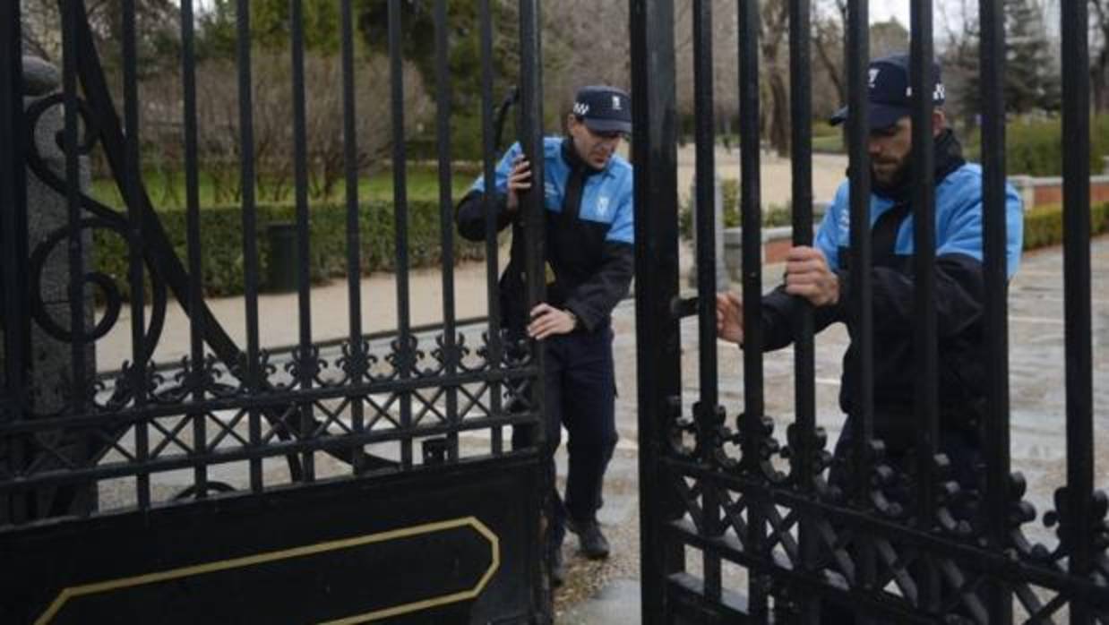 Dos agentes cierran una de las puertas del parque del Retiro