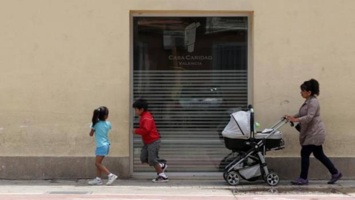 Una familia pasa junto al comedor social de Cáritas en Valencia