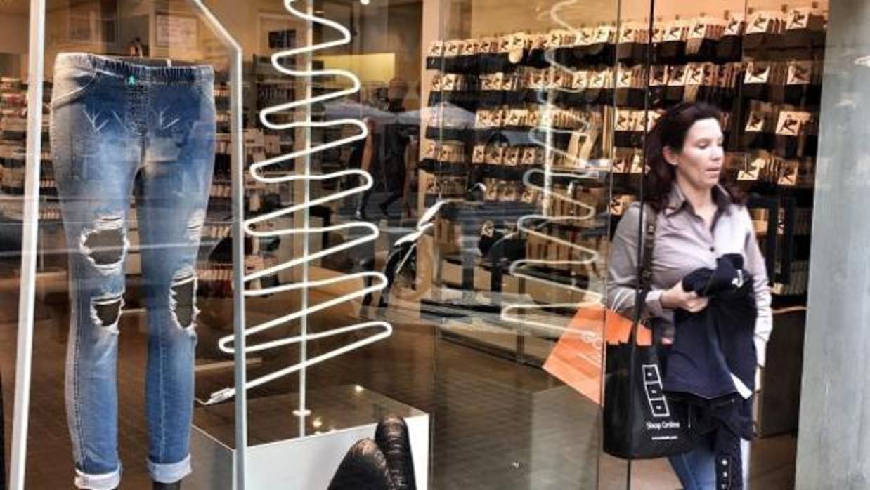 Una consumidora pasa junto a un escaparate al salir de una tienda de ropa en Valencia