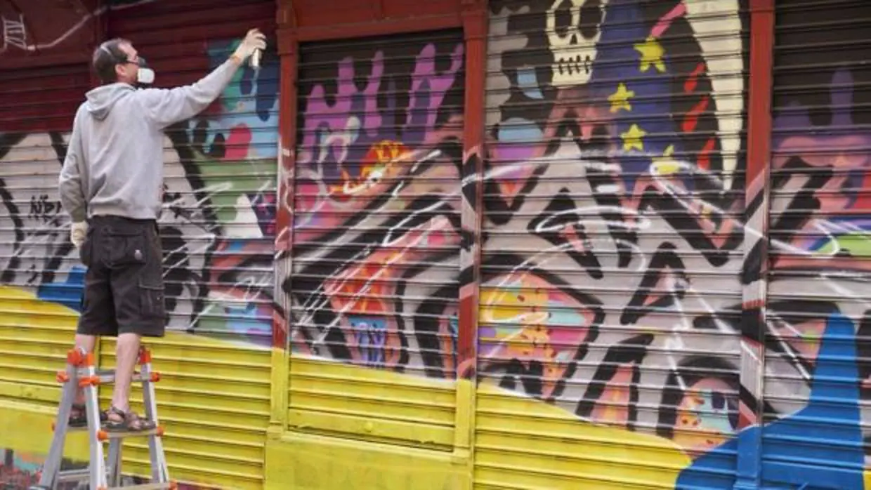 Un grafitero pinta el cierre de una tienda, durante la edición anterior