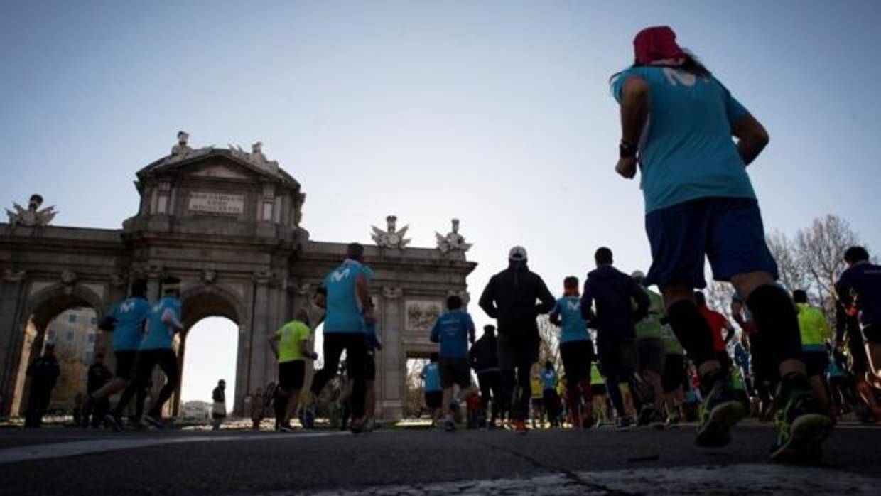 Varios participantes del Maratón pasan junto a la Puerta de Alcalá