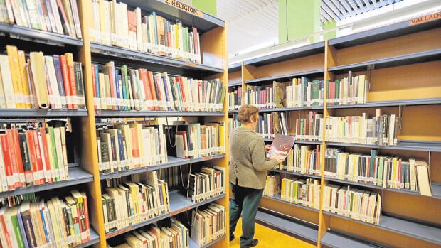 Una mujer consulta un ejemplar en una biblioteca de Valladolid
