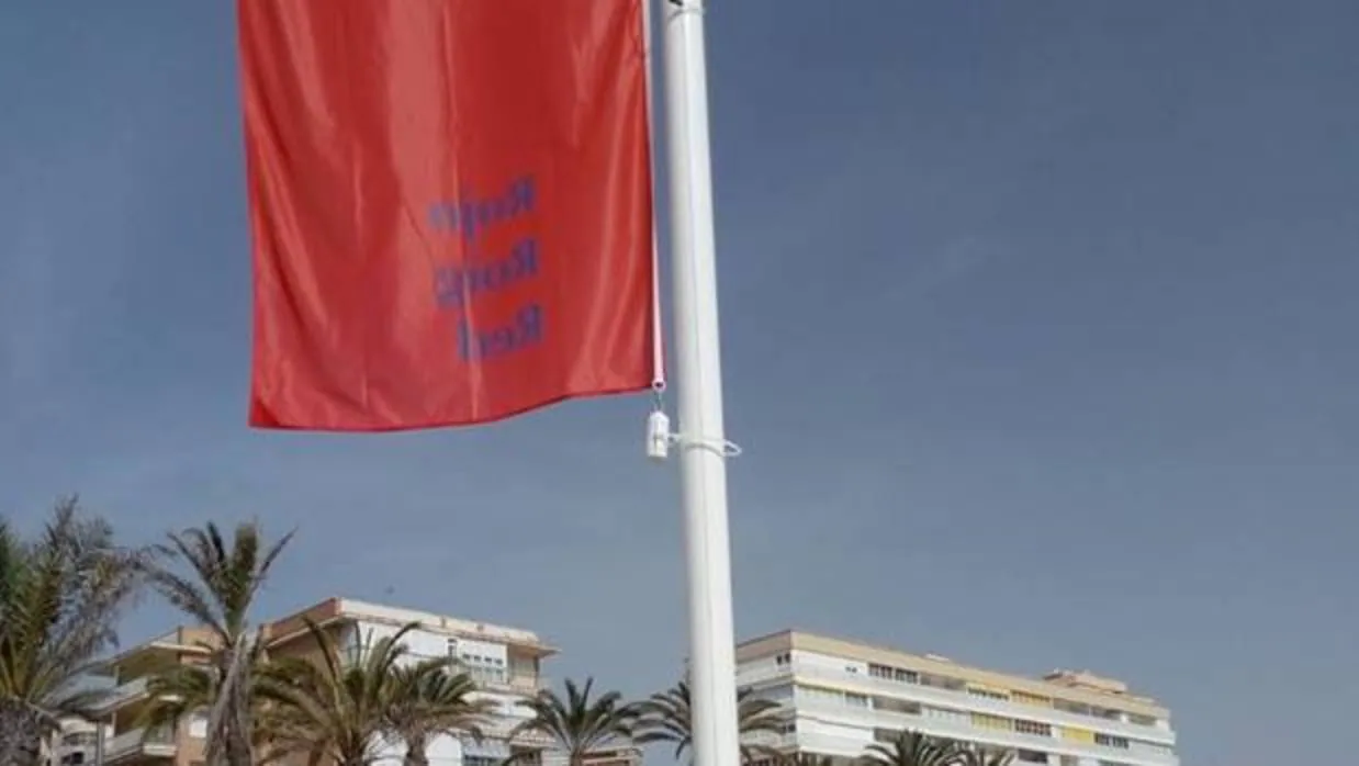 Un empleado municipal de Alicante iza la bandera roja en una de las playas afectadas